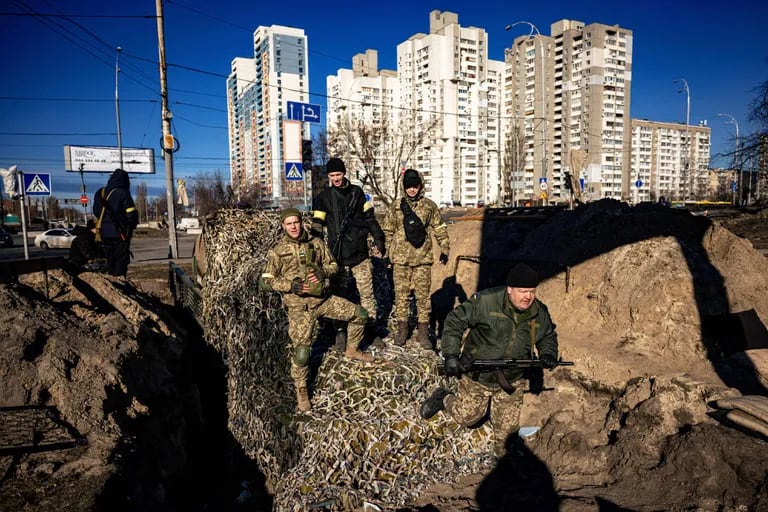 Residentes y voluntarios de Kiev se colocan encima de un APC mientras preparan un puesto de retaguardia con trincheras en Kiev el 28 de febrero de 2022.