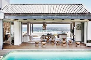 Un patio interno con deck y pileta, donde los banquitos ‘Ball’ de madera maciza (Weylandts) se multiplican en un simpático gesto deco
