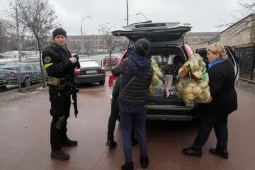 El líder del popular grupo de rock ucraniano Boombox Andriy Khlyvnyuk, miembro de la defensa territorial, a la izquierda, se para cerca de su automóvil después de comprar alimentos para civiles escondidos en un refugio en Kiev, Ucrania, el miércoles 2 de marzo de 2022