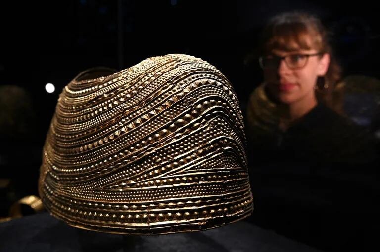 Una empleada del museo mira a la Mold Gold Cape, que data del 1900-1600 AC. La pieza fue encontrada en Flintshire, Wales. (Photo by Daniel LEAL / AFP)