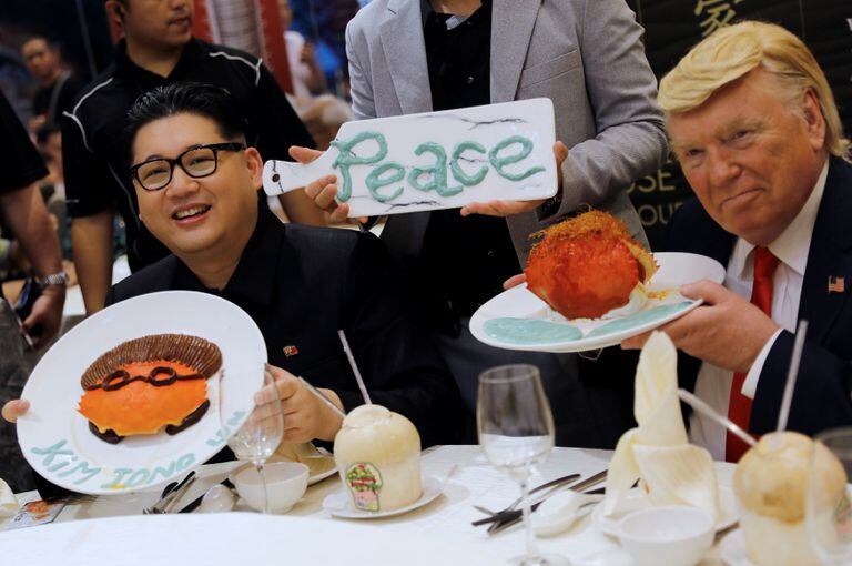 Dos actores que reprensentan a los líderes Donald Trump y Kim Jong-un promocionan un restaurant en Singapore, mientras los verdaderos líderes firman el acuerdo en Sentosa