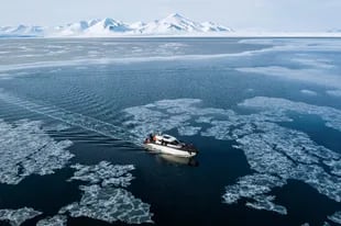 Esta imagen de vista aérea tomada el 3 de mayo de 2022 muestra un barco turístico híbrido que combina un motor diésel y baterías eléctricas, mientras se abre paso en el hielo marino en la bahía de Borebukta, ubicado en el lado noroeste de Isfjorden, en el archipiélago noruego de Svalbard. (Photo by Jonathan NACKSTRAND / AFP)