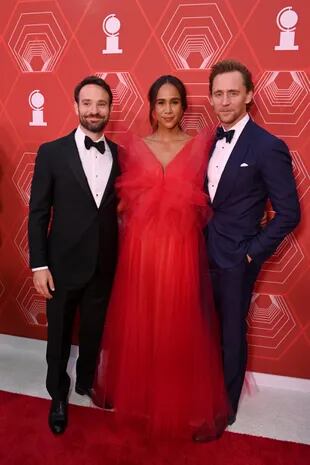 Con esmoquin de seda y lino en color azul marino, Tom Hiddleston posa junto a su pareja, la dramaturga Zawe Ashton, y el actor Charlie Cox