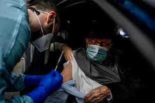 Un trabajador sanitario administra una dosis de la vacuna COVID-19 a un anciano, en las instalaciones del Hospital Militar Baggio de Milán, Italia, el 4 de marzo de 2021