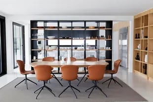 La biblioteca abierta de hierro y madera es un diseño de las arquitectas, al igual que la mesa rodeada con sillas de cuero con patas de hierro (Bo Concept).