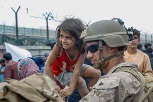 Un marine junto a una pequeña afgana