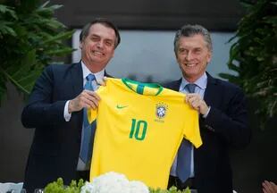 El presidente de Brasil, Jair Bolsonaro junto al presidente Mauricio Macri sostienen la casaca de la selección brasileña