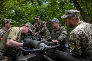 Los soldados con la 55ª Brigada de Artillería Separada de Ucrania limpian y realizan tareas de mantenimiento en un obús M777