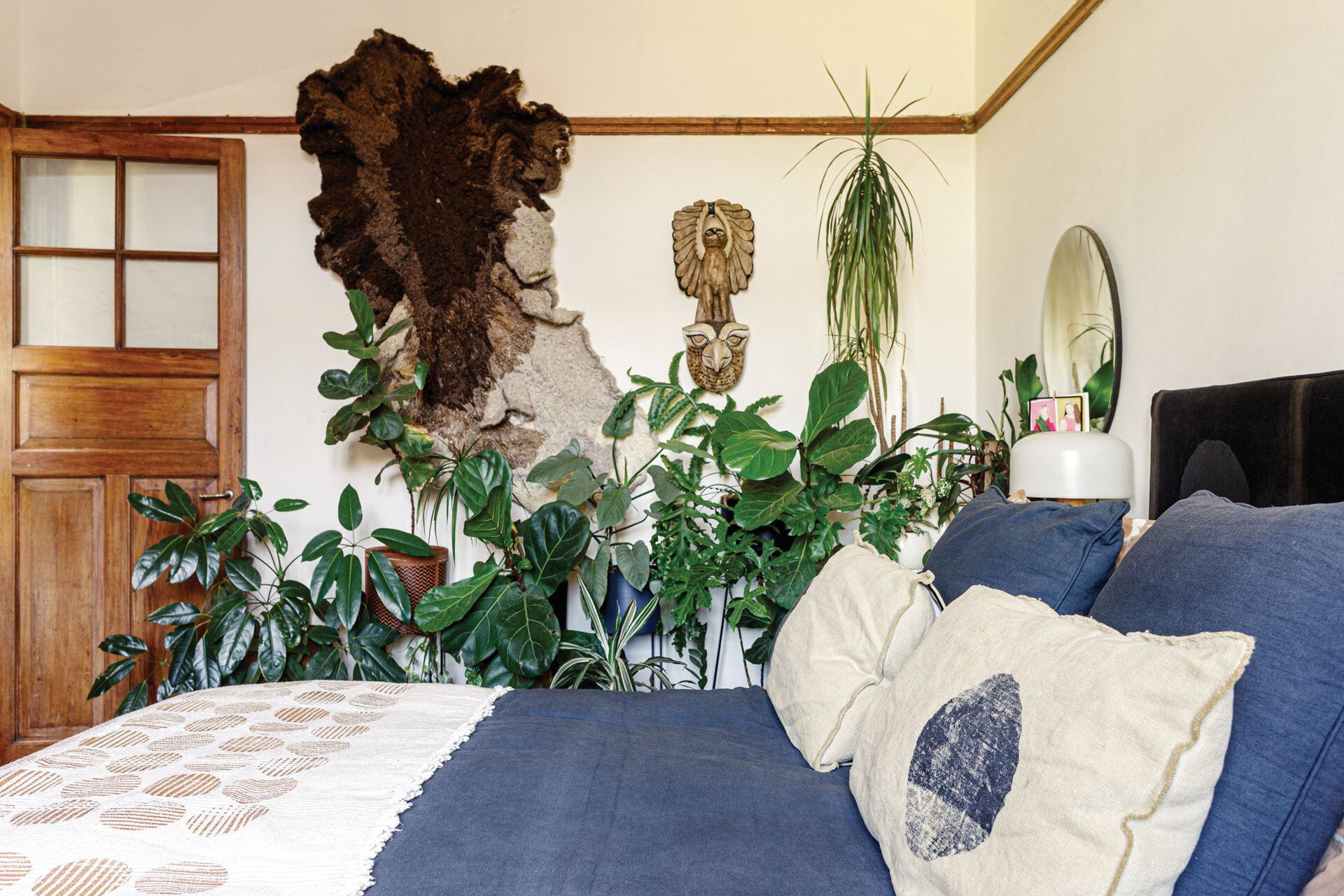 El tapiz de lana natural en tonos de marrón (Vera Somlo) y las plantas le dan al dormitorio un aire exuberante y silvestre.