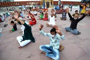 Los devotos hindúes hacen un gesto mientras asisten a las oraciones nocturnas en Har Ki Pauri Ghat, a orillas del río Ganges, después de que el gobierno alivió un bloqueo nacional impuesto como medida preventiva contra el coronavirus