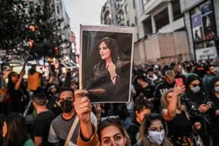Una manifestante sostiene un retrato de Mahsa Amini durante una manifestación en apoyo de Amini, una joven iraní que murió tras ser detenida en Teherán por la policía de la moral de la República Islámica