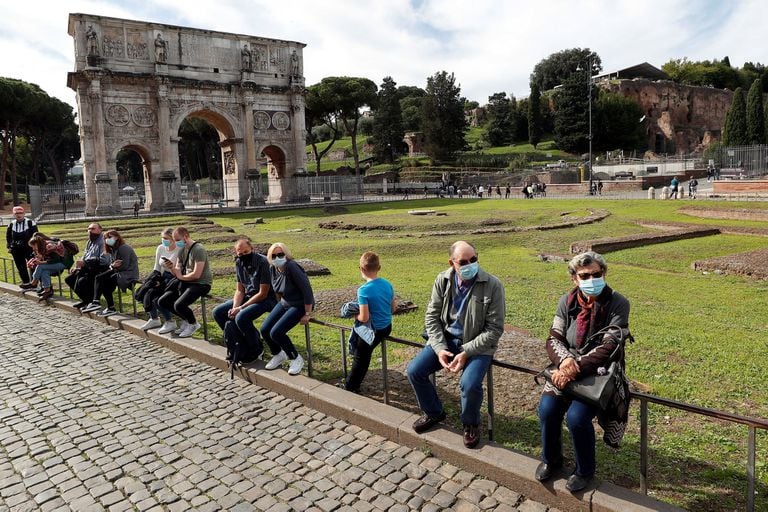Mentre l'Italia adotta nuove restrizioni volte a frenare l'aumento delle infezioni da virus corona (COVID-19) a Roma, i portatori di maschere sono visti accanto all'Arco di Costantino.