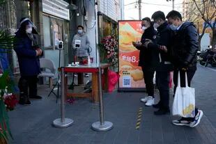Residentes muestran sus códigos de salud para ingresar a un local comercial en Pekín