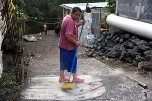 Una mujer barre las cenizas después de una erupción