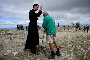 Un peregrino es bendecido por el recién ordenado padre Gerard Quirke después de la Misa en la cumbre de la montaña santa Croagh Patrick