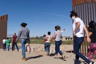 Sekelompok migran Brasil melintasi sebuah lubang di perbatasan antara Amerika Serikat dan Meksiko, Senin, 8 Juni 2021, di Yuma, Arizona (File)