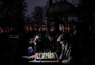 Unos hombres juegan al ajedrez mientras ven con una linterna durante el apagón ene Kiev.
