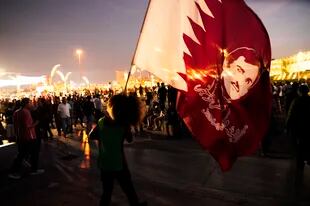 La figura del emir está presente a cada paso en Doha, incluso en las banderas de estos hinchas qataries (AP Photo/Jon Gambrell)