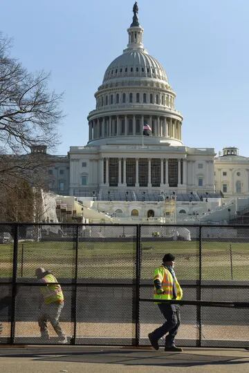 Trabajadores instalan vallas frente al Capitolio luego de los desmanes de ayer