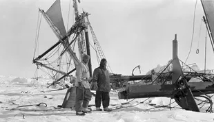 Shackleton (R) observa los restos rotos de su barco justo antes de que se hundiera en las profundidades