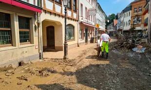 Un hombre despeja escombros con una carretilla a través de las calles del pueblo afectado por la inundación Ahrweiler, Alemania.
