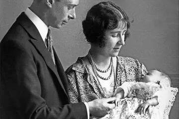Lady Elizabeth Angela Marguerite Bowes-Lyon, hija del decimocuarto conde de Strathmore, la duquesa de York  y su esposo, el príncipe George, duque de York, sostienen a su hija, la princesa Isabel, futura reina de Gran Bretaña, en 1926