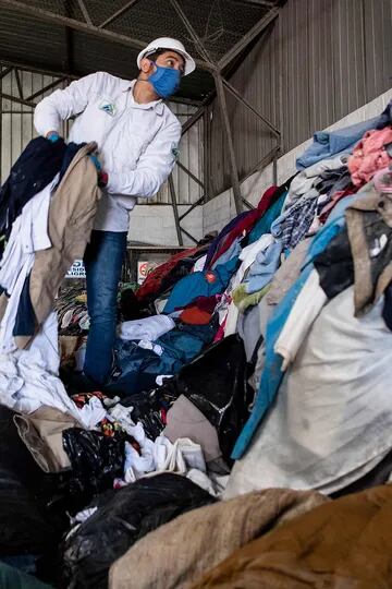 Hombres trabajan en una fábrica que recicla ropa usada desechada en el desierto de Atacama para paneles de aislamiento de madera para los muros de viviendas sociales