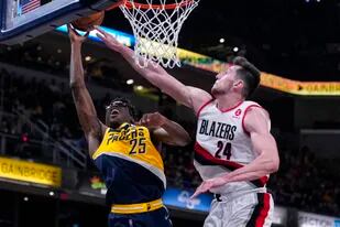 Jalen Smith (25), de los Pacers de Indiana, dispara ante la presión e intento de bloqueo de Drew Eubanks (24), de los Trail Blazers de Portland, durante la segunda mitad del juego de baloncesto de la NBA, en Indianápolis, el domingo 20 de marzo de 2022. (AP Foto/Michael Conroy)