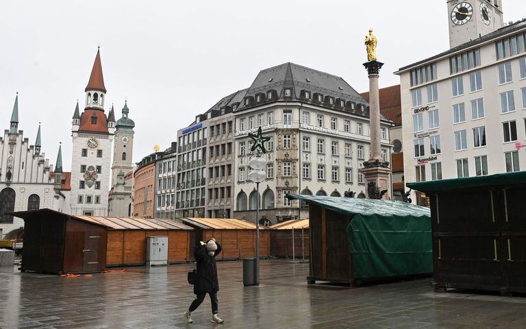 Una mujer pasa frente a los puestos cerrados del mercado navideño en Marienplatz en el centro de Múnich, en el sur de Alemania, el 22 de noviembre de 2021, en medio de un aumento de infecciones durante la pandemia de coronavirus