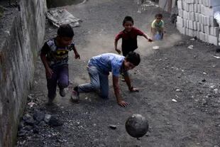 Chicos juegan al fútbol entre las cenizas