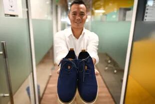 El emprendedor vietnamita Le Thanh muestra un par de zapatos fabricados a partir de poso de café, en su empresa ecológica ShoeX, el 29 de junio de 2020 en Ciudad Ho Chi Minh