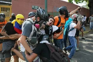 Un manifestante es llevado después de que fue afectado por gas lacrimógeno lanzado por las fuerzas de seguridad