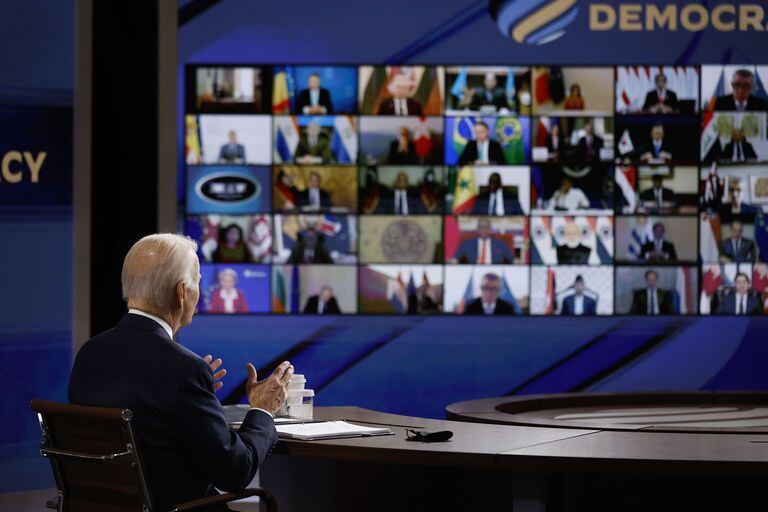 El presidente de los Estados Unidos, Joe Biden, mira una pantalla de video que muestra a los participantes en la Cumbre para la Democracia mientras pronuncia los comentarios de apertura en el Auditorio de South Court el 9 de diciembre de 2021 en Washington, DC.