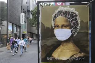 Hasta la Mona Lisa en un afiche publicitario de una peluquería usa barbijo en las calles de Seúl, Corea del Sur