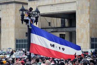 Un hombre cuelga una bandera del M-19 (Movimiento 19 de Abril) -un antiguo grupo guerrillero que se convirtió en el partido político Alianza Democrática en los años 90- antes del inicio de la ceremonia de investidura del nuevo presidente de Colombia, Gustavo Petro, en la plaza de Bolívar de Bogotá, el 7 de agosto de 2022.