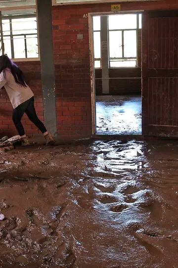 Maestros y estudiantes limpian el lodo dentro de un salón de clases luego de las inundaciones en la escuela secundaria Brettenwood, cerca de Durban