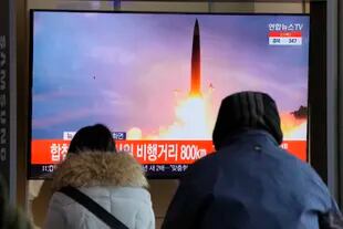 Varias personas ven en una pantalla una imagen de archivo de un noticiario relacionada con el lanzamiento de un misil norcoreano mientras esperan en la central ferroviaria de Seúl, en Corea del sur, el domingo 30 de enero de 2022. (AP Foto/Ahn Young-joon)
