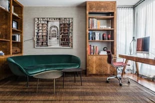 El sofá ‘Russell’ de terciopelo verde (Minotti) se complementa con las mesitas ‘Louisa’ (Molteni) y dos bibliotecas de raíz de nogal (Estudio Paula Gutiérrez).