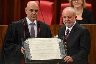 Brazilian President-elect Luis Inacio da Silva receives a certificate diploma from the President of the High Electoral Tribunal (TSE), Alexandre de Moraes, during a ceremony at the TSE headquarters in Brasilia on December 12, 2022.