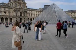 I turisti scattano foto davanti alla piramide del Museo del Louvre a Parigi