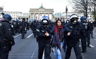 La policía detiene a una manifestante durante las protestas contra el nuevo paquete de restricciones por el coronavirus frente al Parlamento en Berlín el 21 de abril de 2021.  