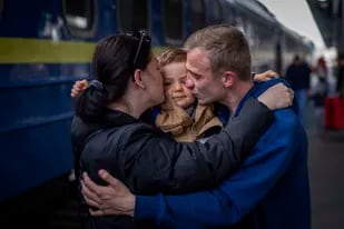 Oleksandr,  de 26 años, besa a su hijo, Egor, de 2 años, y a su esposa, Alyona, de 26, al reunirse en la estación de tren después de más de dos meses separados por la guerra en Kiev, Ucrania, el sábado 23 de abril de 2022. (AP Foto/Emilio Morenatti)