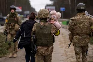 A Ukrainian soldier carries a baby helping a fleeing family to cross the Irpin river in the outskirts of Kyiv, Ukraine, Saturday, March 5, 2022. (AP Photo/Emilio Morenatti)