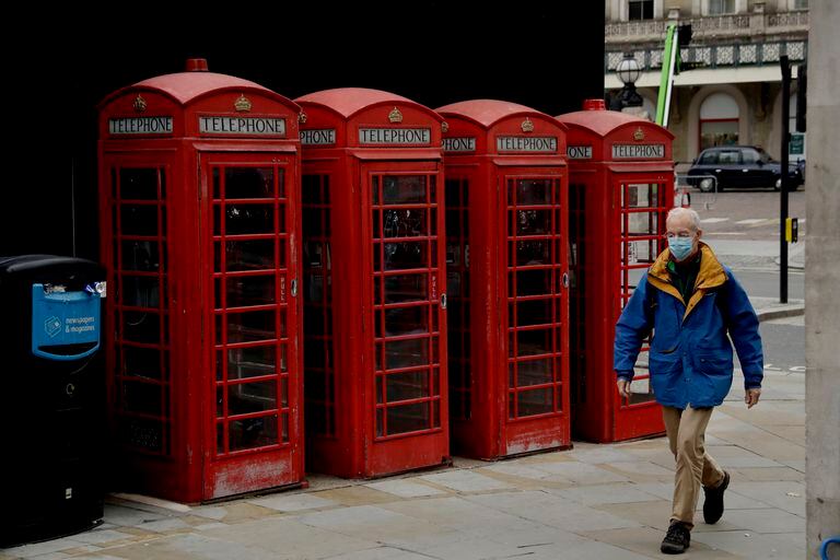 ARCHIVO - Un hombre camina junto a una tradicional cabina telefónica en Londres el 20 de noviembre del 2020. Miles de las icónicas cabinas telefónicas rojas en Gran Bretaña serán protegidas de retiro bajo nuevas reglas, dijo el 9 de noviembre del 2021 el regulador de telecomunicaciones del Reino Unido. (AP Foto/Matt Dunham)