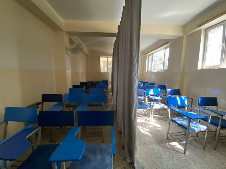 Una cortina en el centro del aula divide a los estudiantes