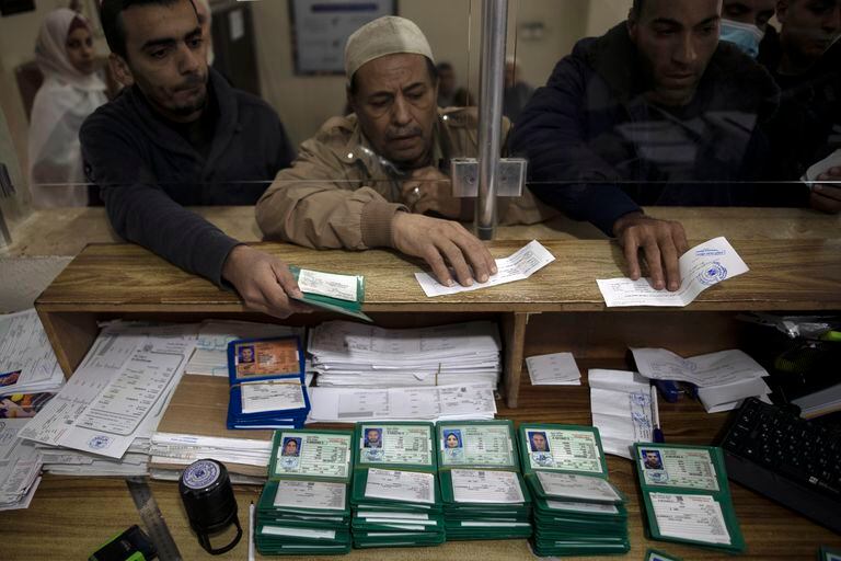 Tres personas recogen sus nuevos documentos nacionales de identidad en una oficina del gobierno en la Ciudad de Gaza el 5 de enero del 2022. (AP Photo/ Khalil Hamra)