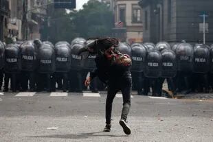 Un manifestante lanza una piedra a la policía antidisturbios durante una protesta contra el acuerdo entre el gobierno argentino y el Fondo Monetario Internacional