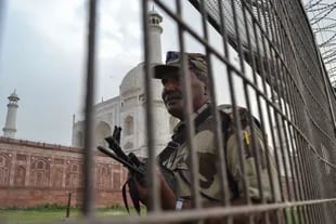 A member of security personnel stands guard behind a perimeter fence at the Taj Mahal.