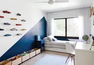 En el cuarto del hijo varón pintaron un triángulo de azul oscuro para cortar el blanco; en la misma pared, colgaron una colección de autitos a modo de exposición.