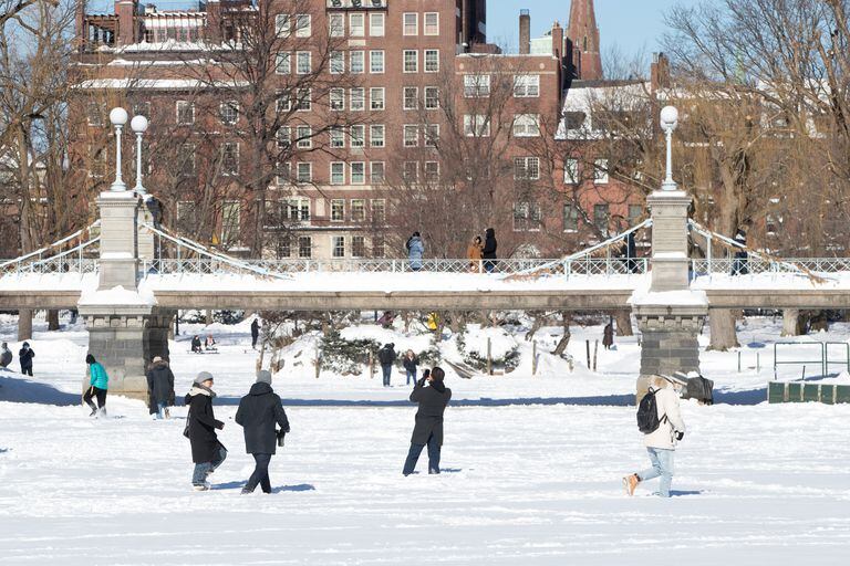 People walk on the frozen, snow-covered pond on Boston Common after Winter Storm Kenan on January 30, 2022 in Boston, Massachusetts.